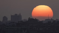 The sun sets behind the buildings in the Gaza Strip as seen from southern Israel. Photo / AP