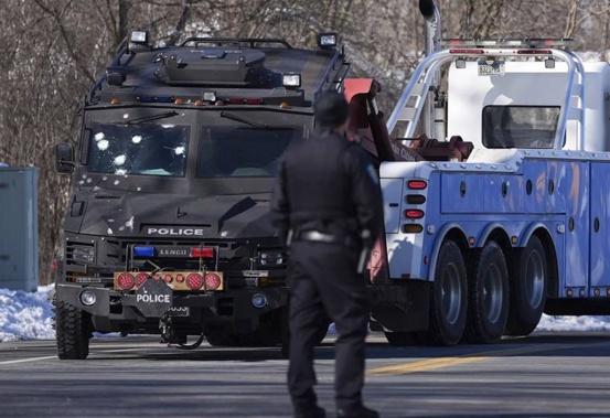 A police vehicle with bullet pockmarks is towed near the scene where two police officers and a first responder were shot and killed. Photo / AP