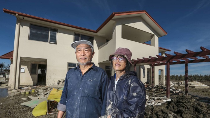 The Zhangs at their two-storey property on Scissons Rd, Pākōwhai, where floodwaters from Cyclone Gabrielle reached the roof. Their dog, Huahua, was lost in the flooding. Photo / Paul Taylor