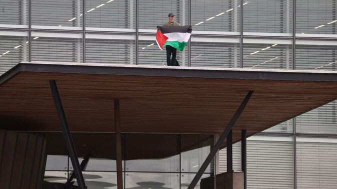 A protester waving a Palestine flag has climbed on to the roof of the Christchurch City Council building.