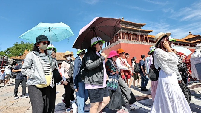 Tourists shield themselves from the sun while visiting the Palace Museum on June 9, 2024 in Beijing, China. Visual China Group/Getty Images