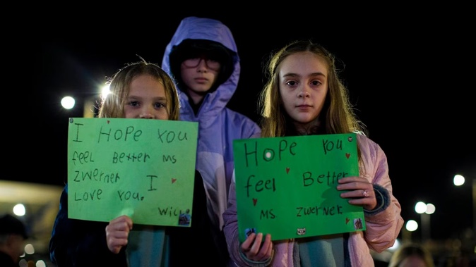 Willow Crawford, left, and her older sister Ava, right, join friend Kaylynn Vestre, center, in expressing their support for Richneck Elementary School first-grade teacher Abby Zwerner during a candlelight vigil in her honour. Photo / AP